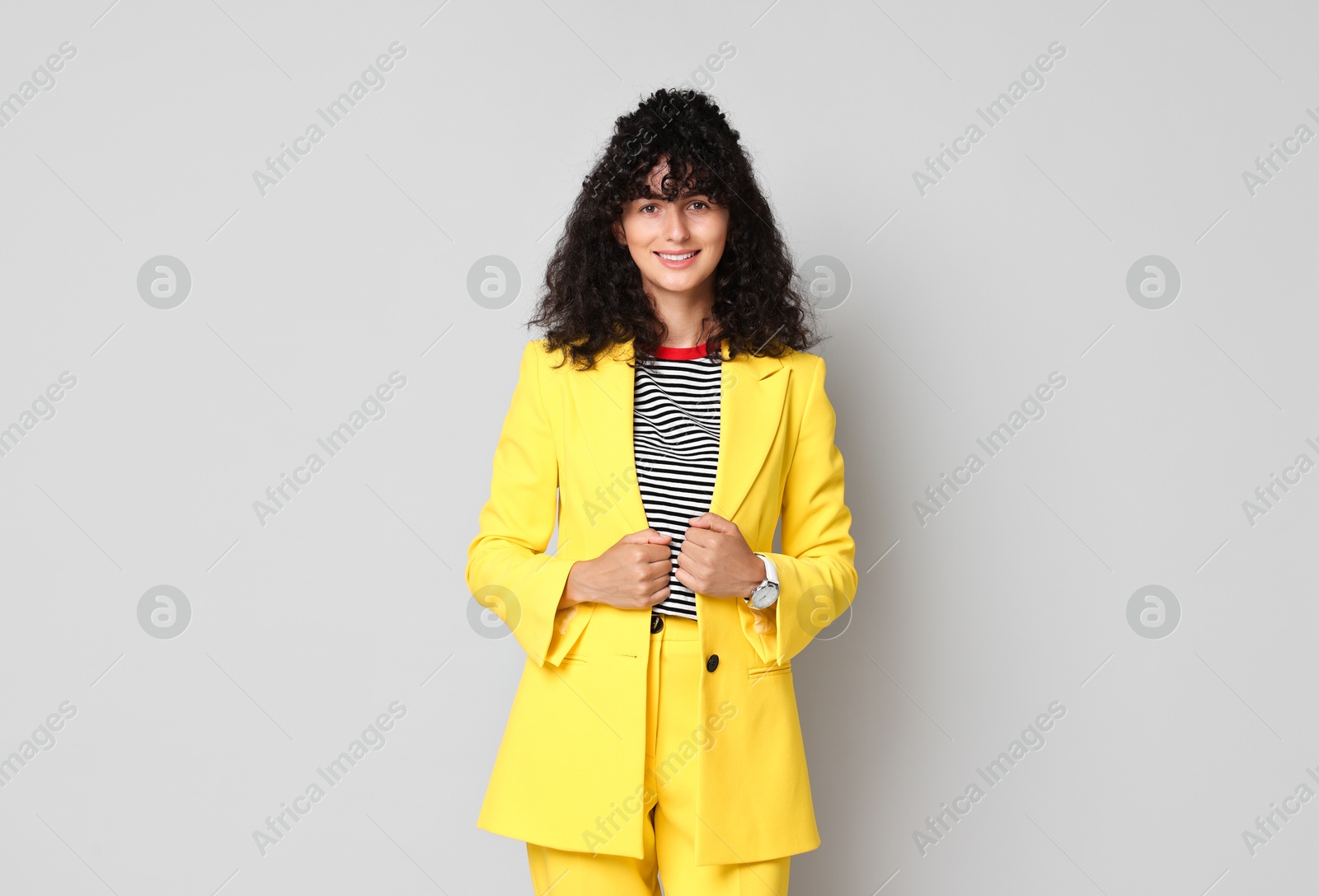 Photo of Beautiful young woman in stylish yellow suit on grey background