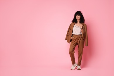 Photo of Beautiful young woman in stylish suit on pink background, space for text