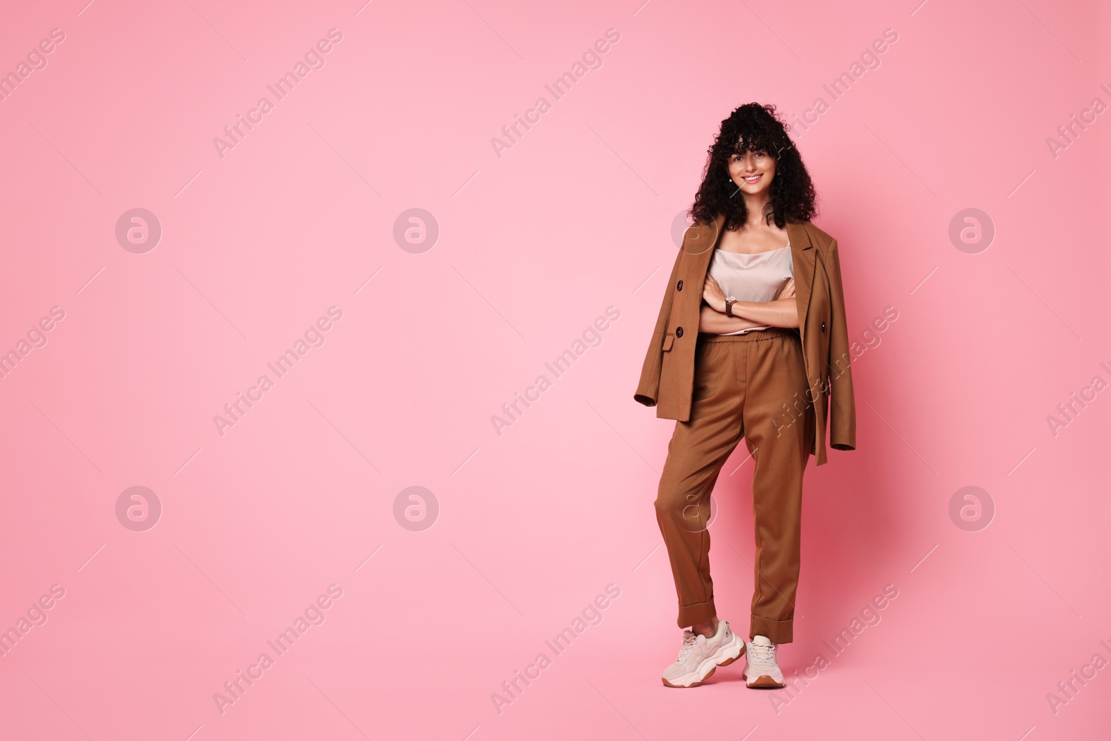 Photo of Beautiful young woman in stylish suit on pink background, space for text