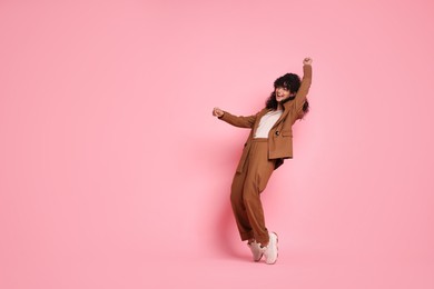 Photo of Beautiful young woman in stylish suit posing on pink background