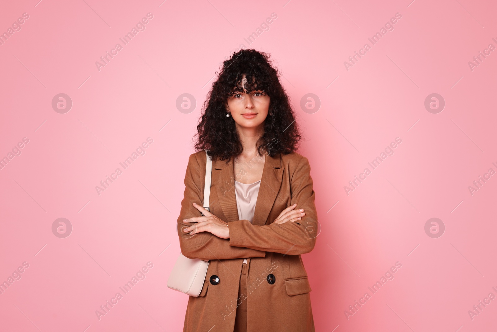 Photo of Beautiful young woman in stylish suit with bag on pink background