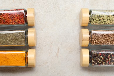 Different spices in glass jars on light grey table, top view. Space for text