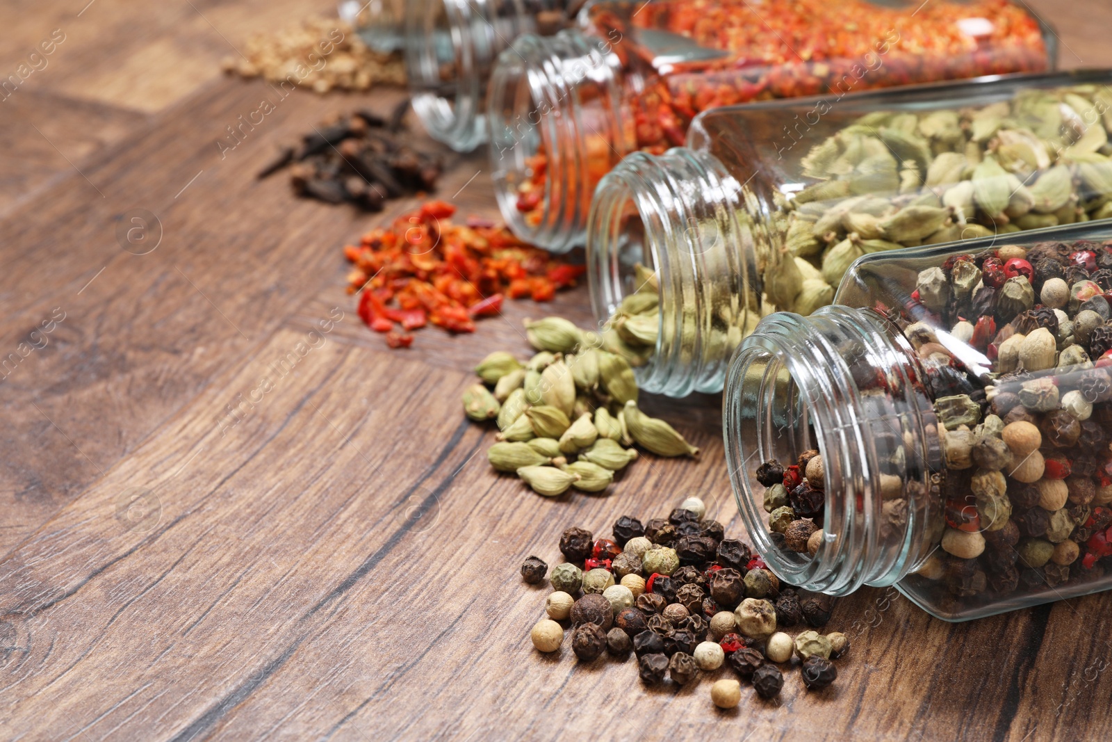 Photo of Different spices in glass jars on wooden table, space for text