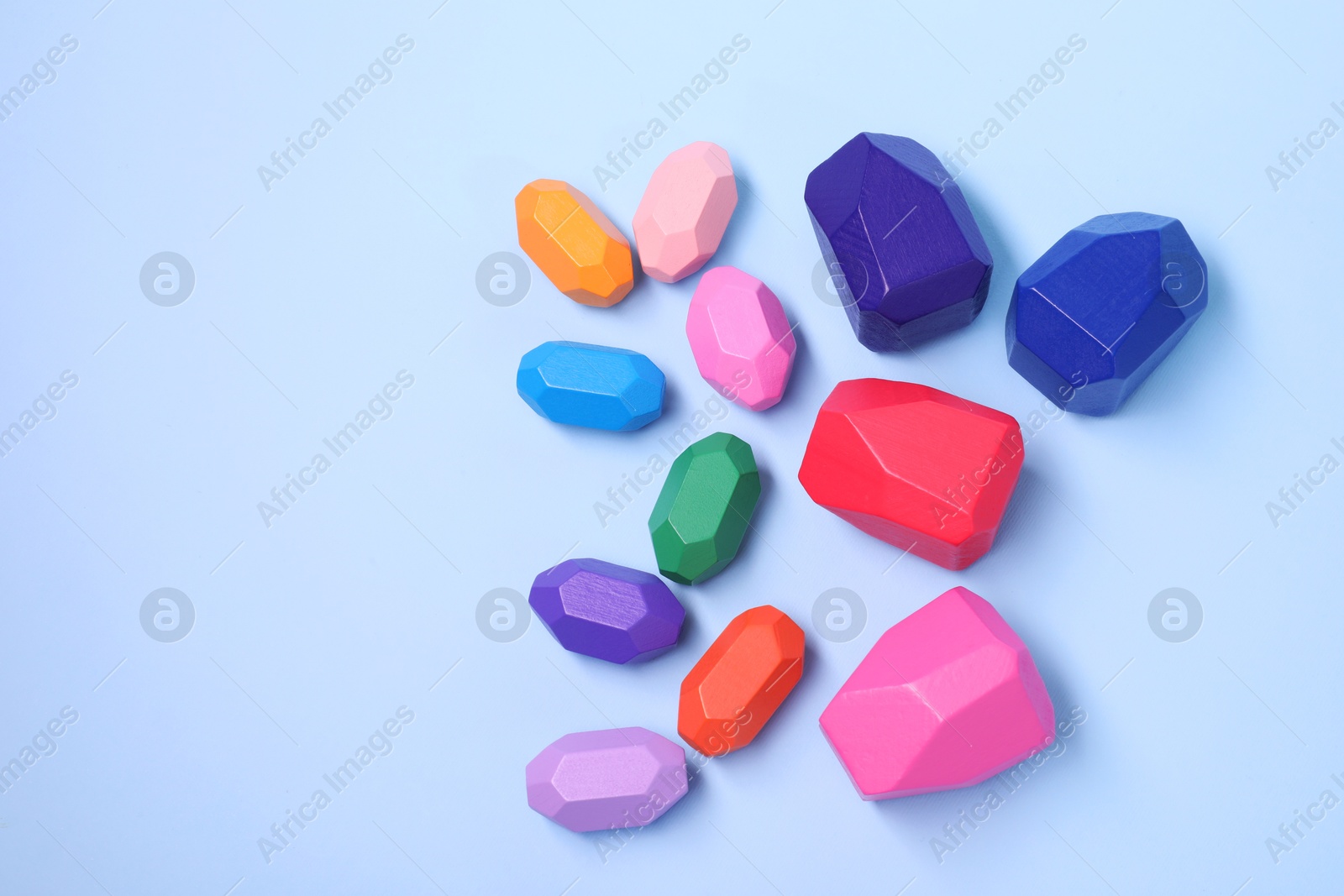 Photo of Many colorful balancing stones on light blue background, top view. Space for text