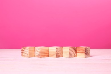 Photo of Many blank wooden cubes on table against pink background, space for text