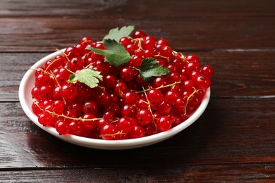 Photo of Fresh red currants and leaves on wooden table, closeup