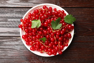 Photo of Fresh red currants and leaves on wooden table, top view