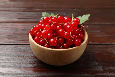 Photo of Fresh red currants in bowl on wooden table, closeup