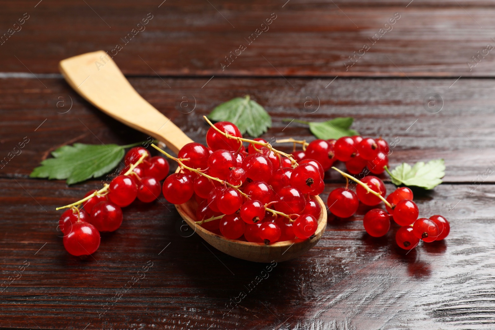 Photo of Fresh red currants in spoon on wooden table, closeup