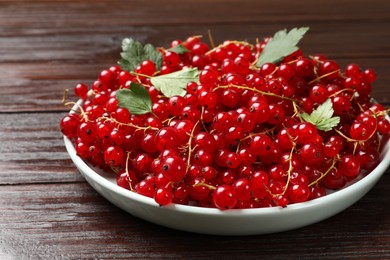 Fresh red currants and leaves on wooden table, closeup