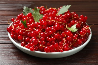 Fresh red currants and leaves on wooden table, closeup