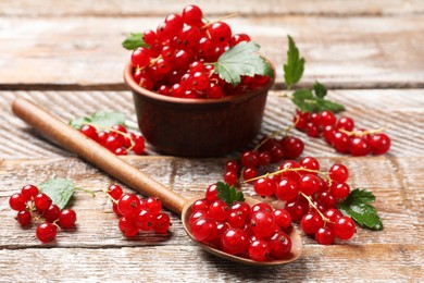 Fresh red currants and green leaves on wooden table, closeup