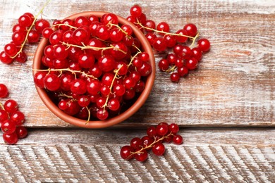 Fresh red currants in bowl on wooden table, top view