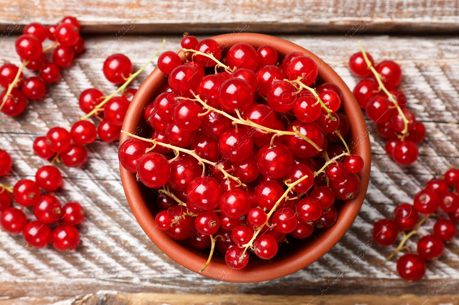 Photo of Fresh red currants in bowl on wooden table, top view