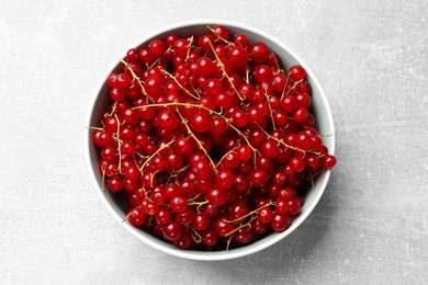 Photo of Fresh red currants in bowl on light grey table, top view