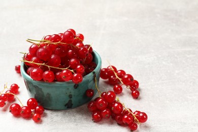 Fresh red currant in bowl on light table. Space for text