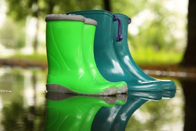 Colorful rubber boots in puddle on city street