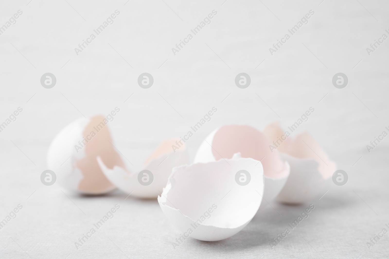 Photo of Broken eggshells on grey textured table, closeup