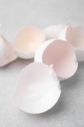 Photo of Broken eggshells on grey textured table, closeup