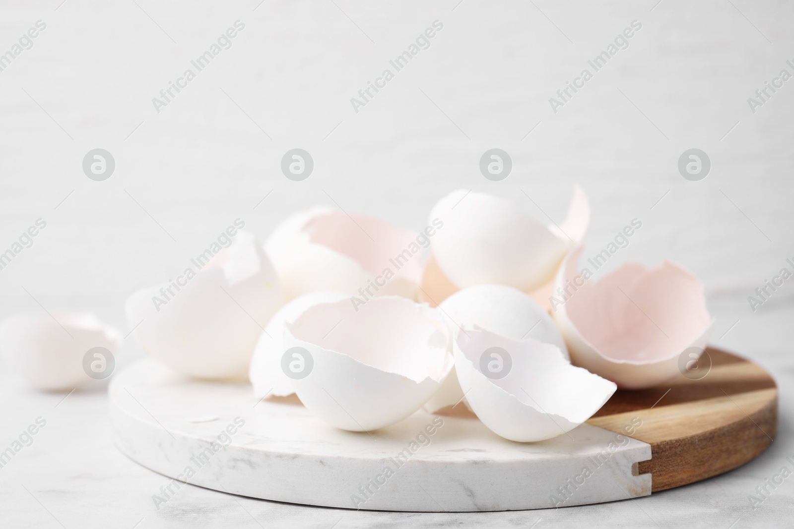 Photo of Broken eggshells on light marble table, closeup