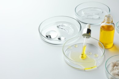 Photo of Petri dishes with different cosmetic products on white background. Space for text