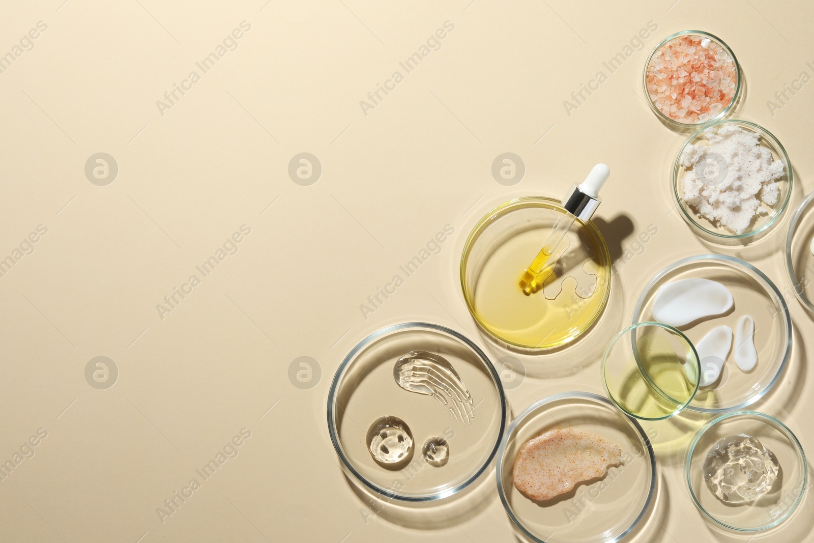 Photo of Petri dishes with different cosmetic products on beige background, flat lay. Space for text