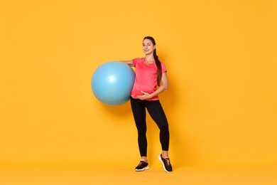 Photo of Beautiful pregnant woman with fitball on yellow background