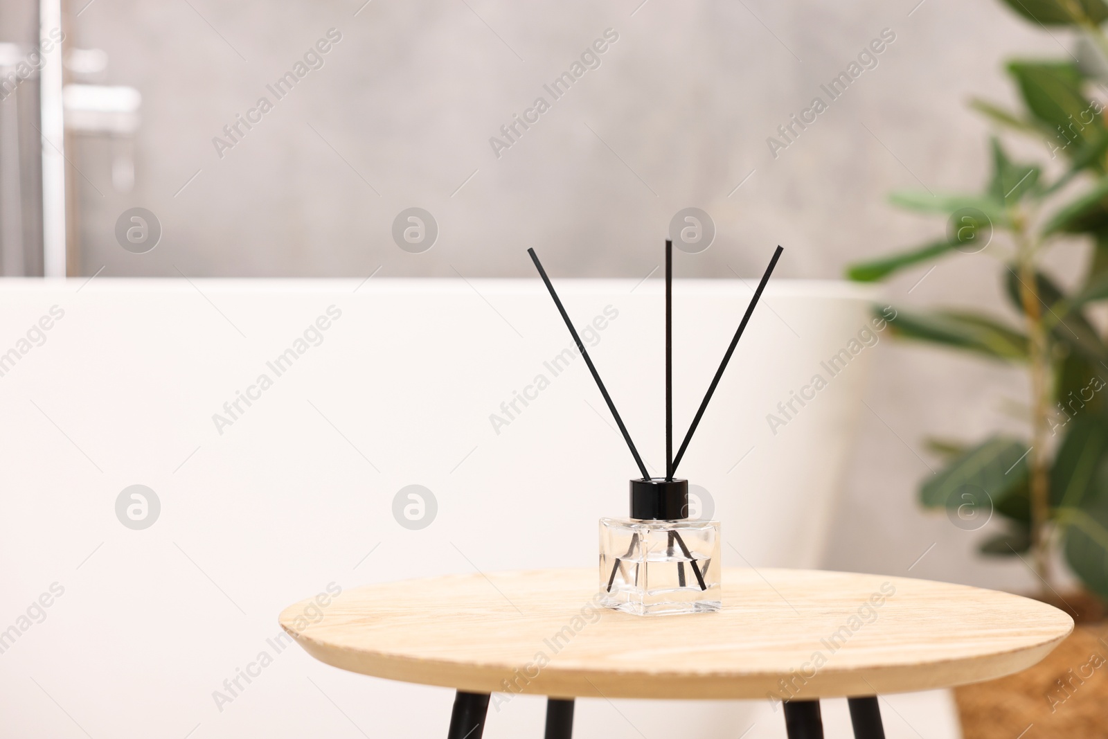 Photo of Reed diffuser on wooden table in bathroom, space for text