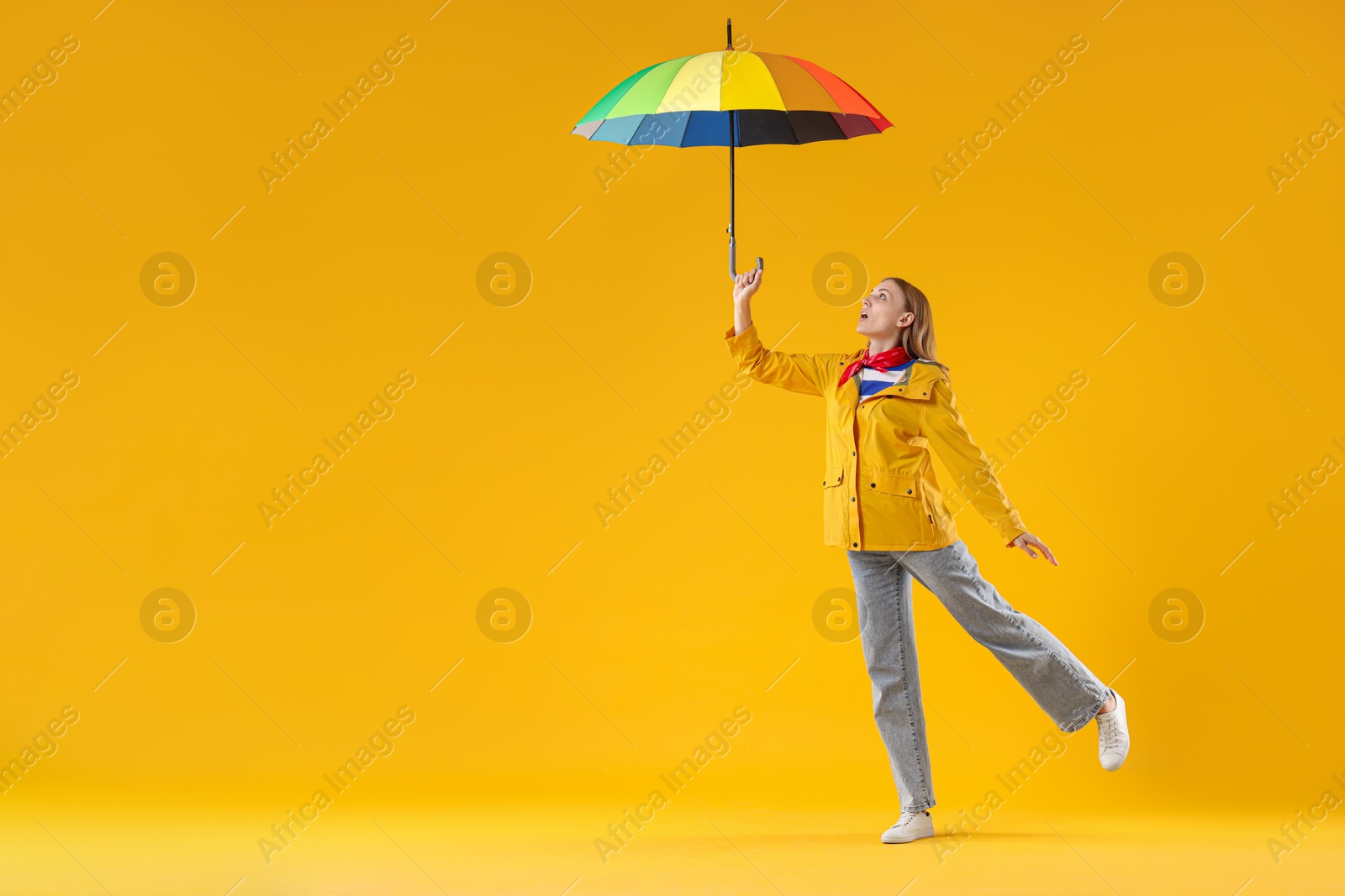 Photo of Woman with colorful umbrella on yellow background, space for text