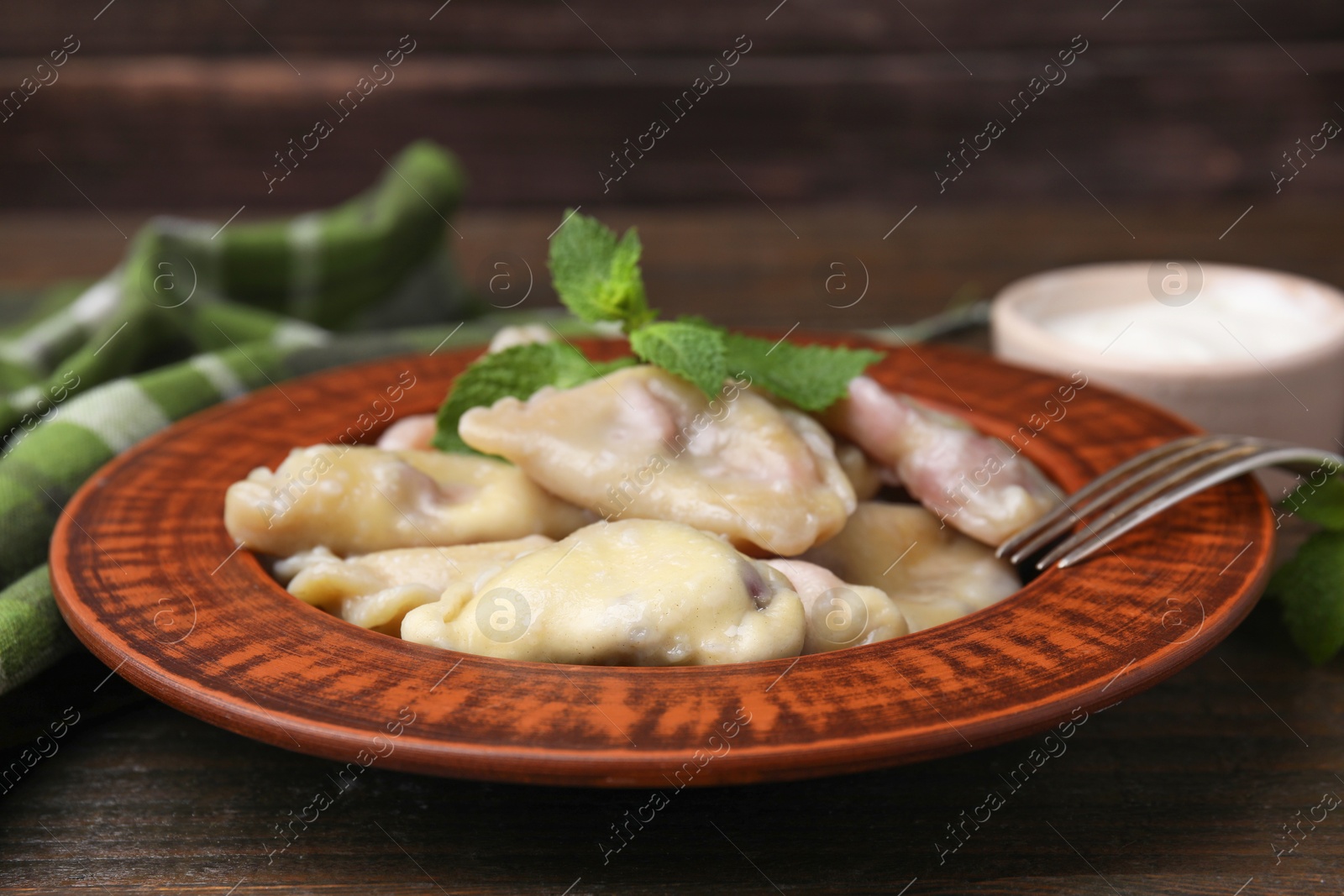 Photo of Traditional Ukrainian dumplings (varenyky) with cherries served on wooden table, closeup