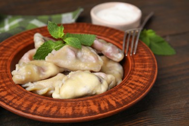 Photo of Traditional Ukrainian dumplings (varenyky) with cherries served on wooden table, closeup