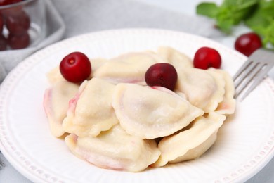 Photo of Traditional Ukrainian dumplings (varenyky) with cherries served on white table, closeup