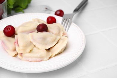 Photo of Traditional Ukrainian dumplings (varenyky) with cherries served on white tiled table, closeup