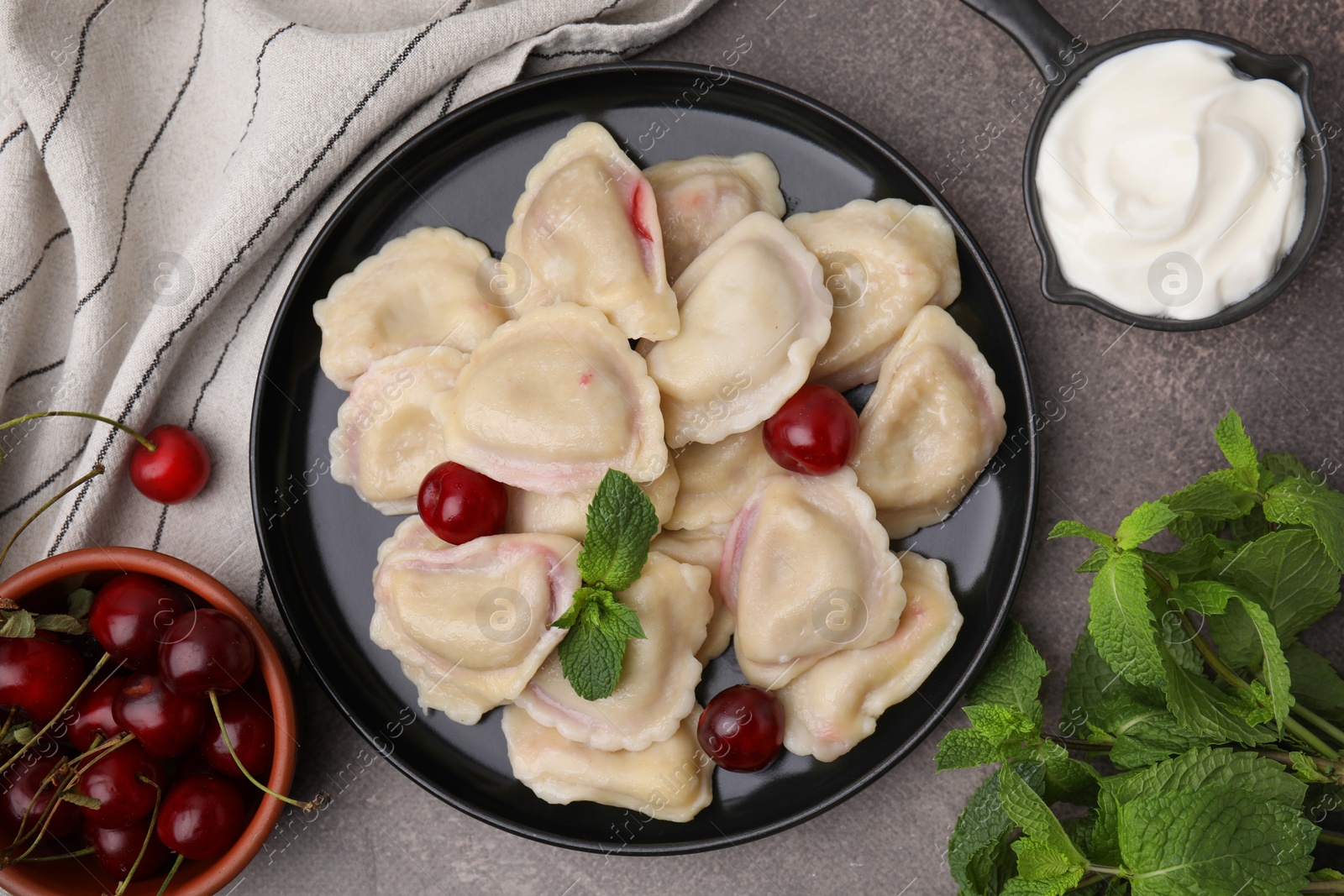 Photo of Traditional Ukrainian dumplings (varenyky) with cherries served on brown table, flat lay