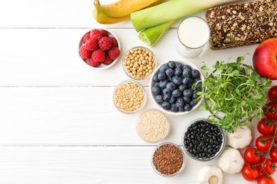 Different fresh products on white wooden table, flat lay and space for text. Source of prebiotics