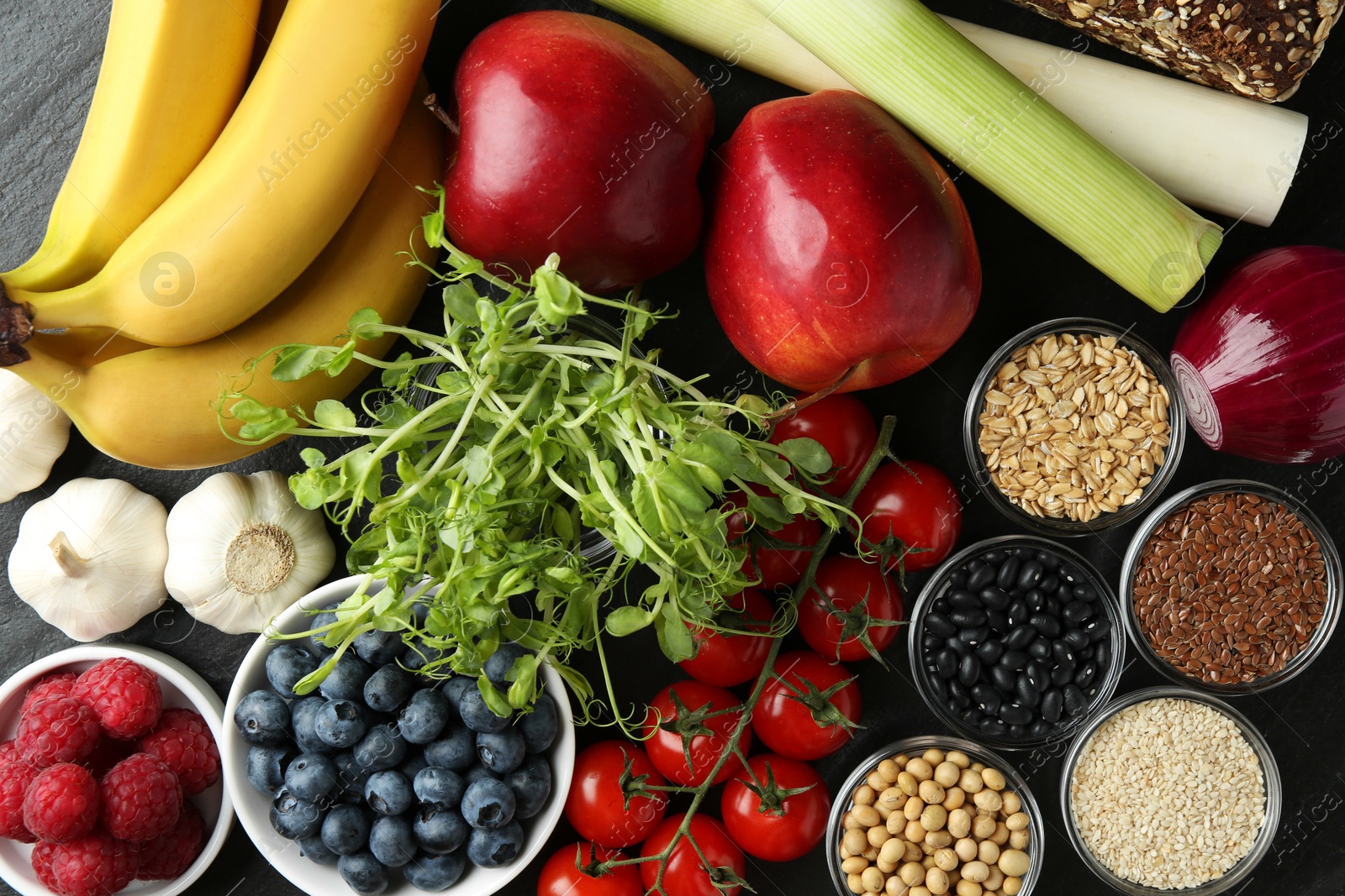 Photo of Different fresh products on black table, flat lay. Source of prebiotics