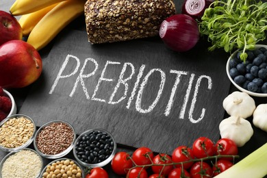 Photo of Slate board with word Prebiotic and different fresh products on black table