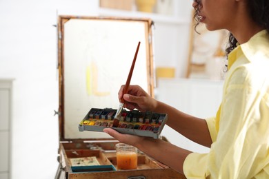 Photo of Woman drawing picture with paint in studio, closeup