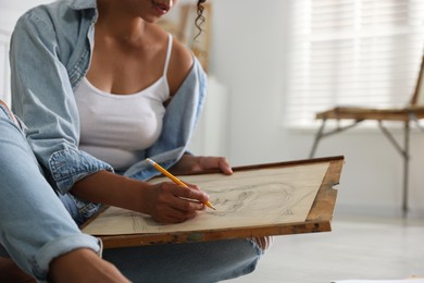 Photo of Woman drawing picture with pencil in studio, closeup