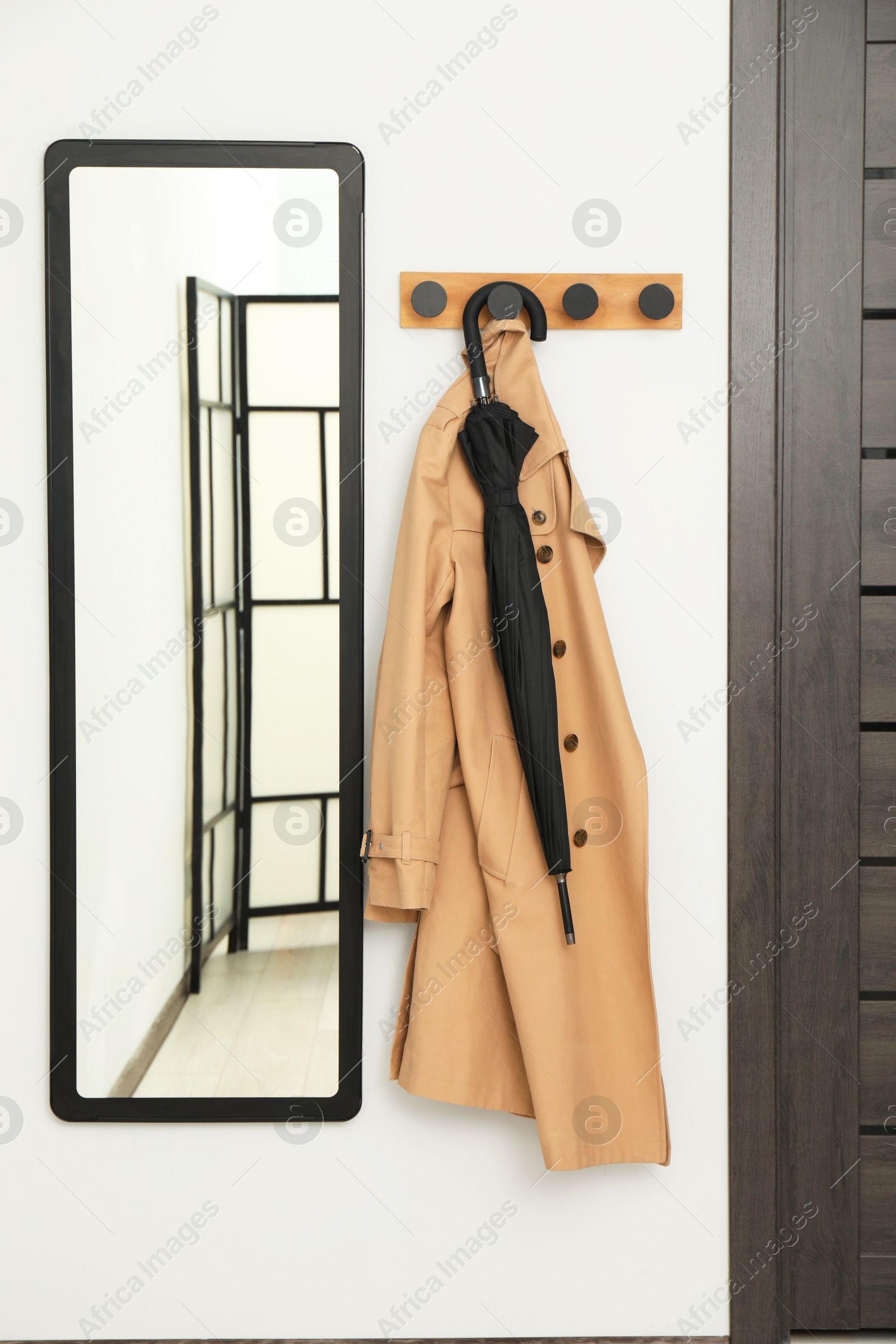 Photo of Black umbrella, coat, rack and mirror in hallway