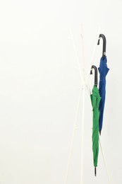 Photo of Colorful umbrellas on clothing rack against white background, space for text