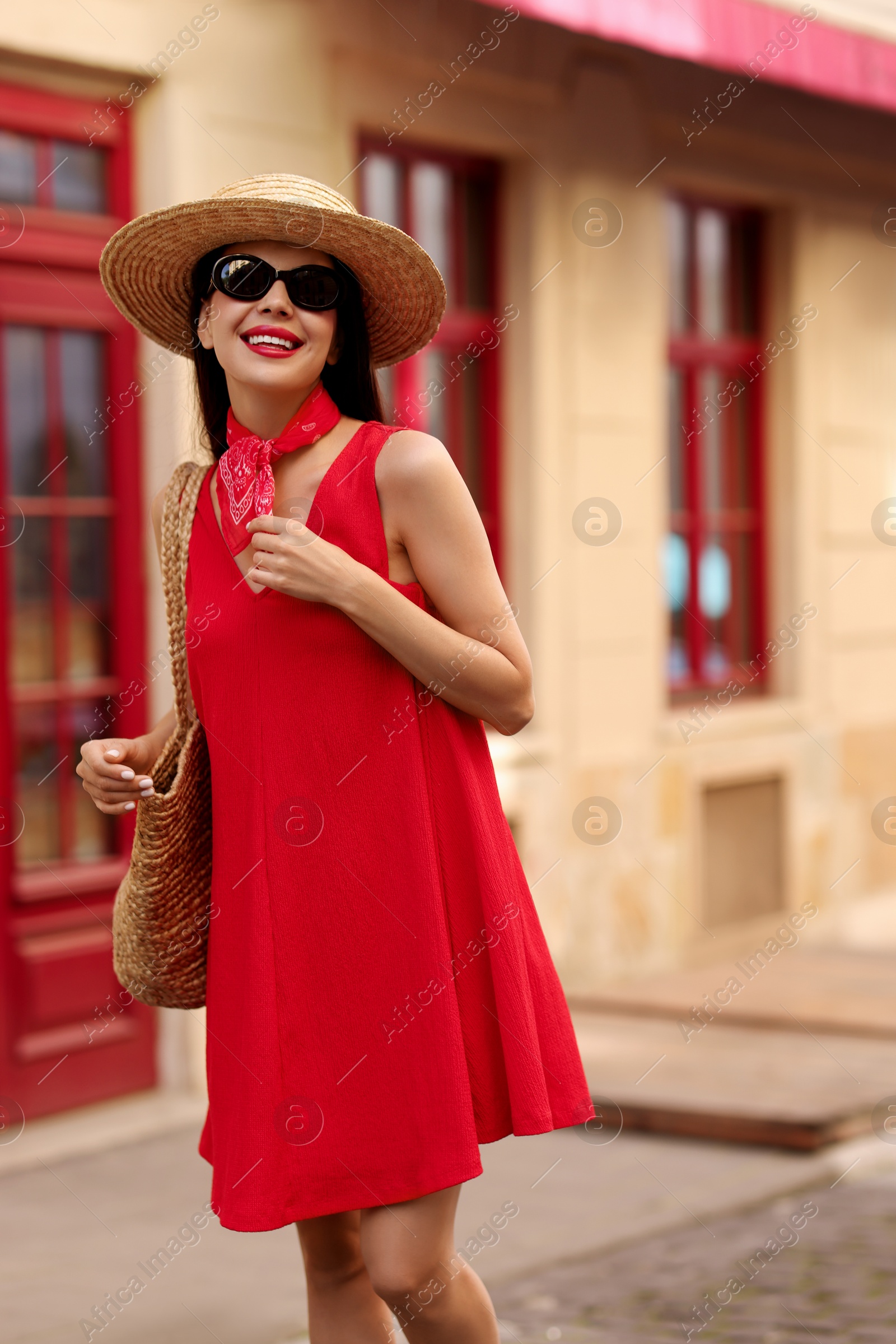 Photo of Smiling young woman in stylish hat and sunglasses on city street