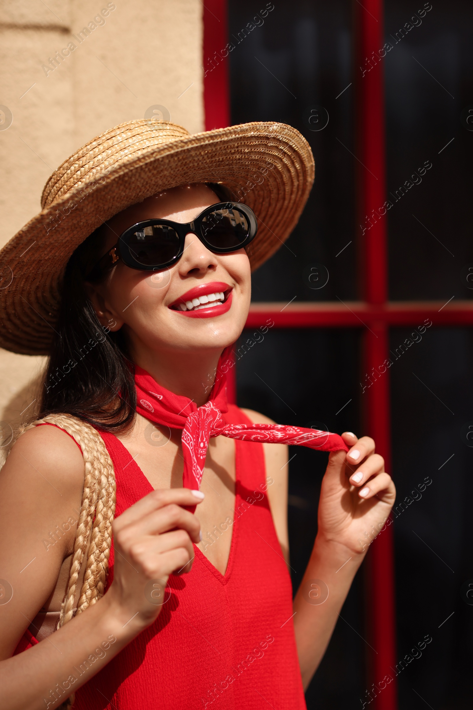 Photo of Smiling young woman in stylish hat and sunglasses near building outdoors