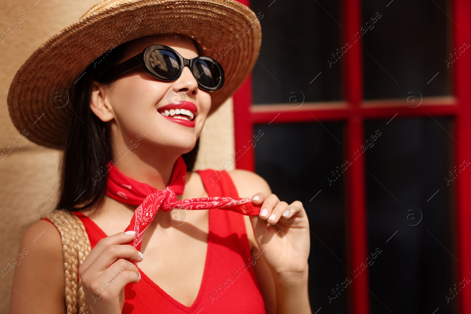 Photo of Smiling young woman in stylish hat and sunglasses near building outdoors