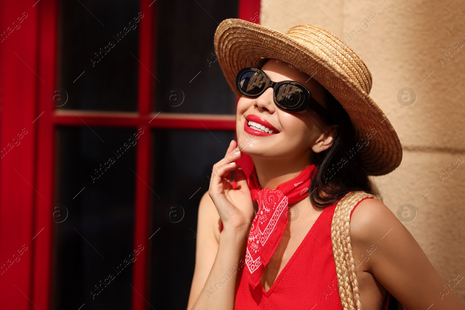 Photo of Smiling young woman in stylish hat and sunglasses near building outdoors