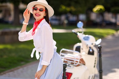 Photo of Smiling young woman in stylish hat and sunglasses on city street