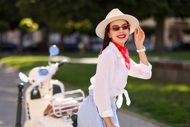 Smiling young woman in stylish hat and sunglasses on city street