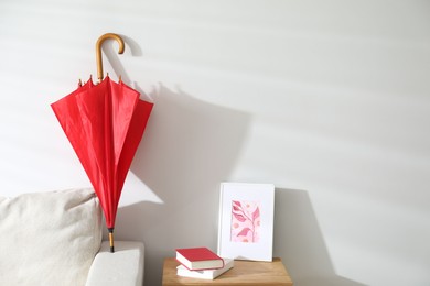 Photo of Red umbrella drying on sofa at home. Space for text