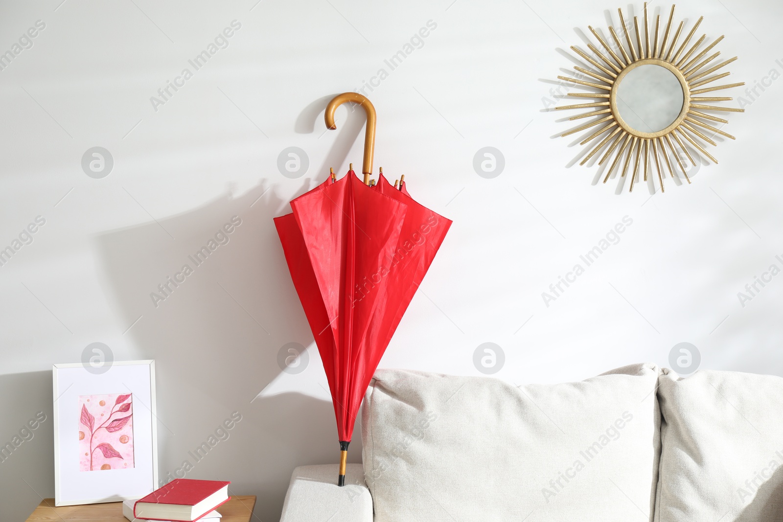 Photo of Red umbrella drying on sofa at home