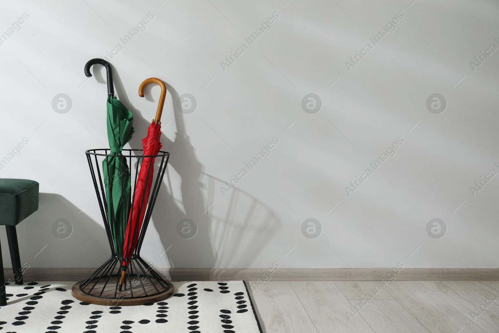 Photo of Colorful umbrellas in stand near light wall. Space for text